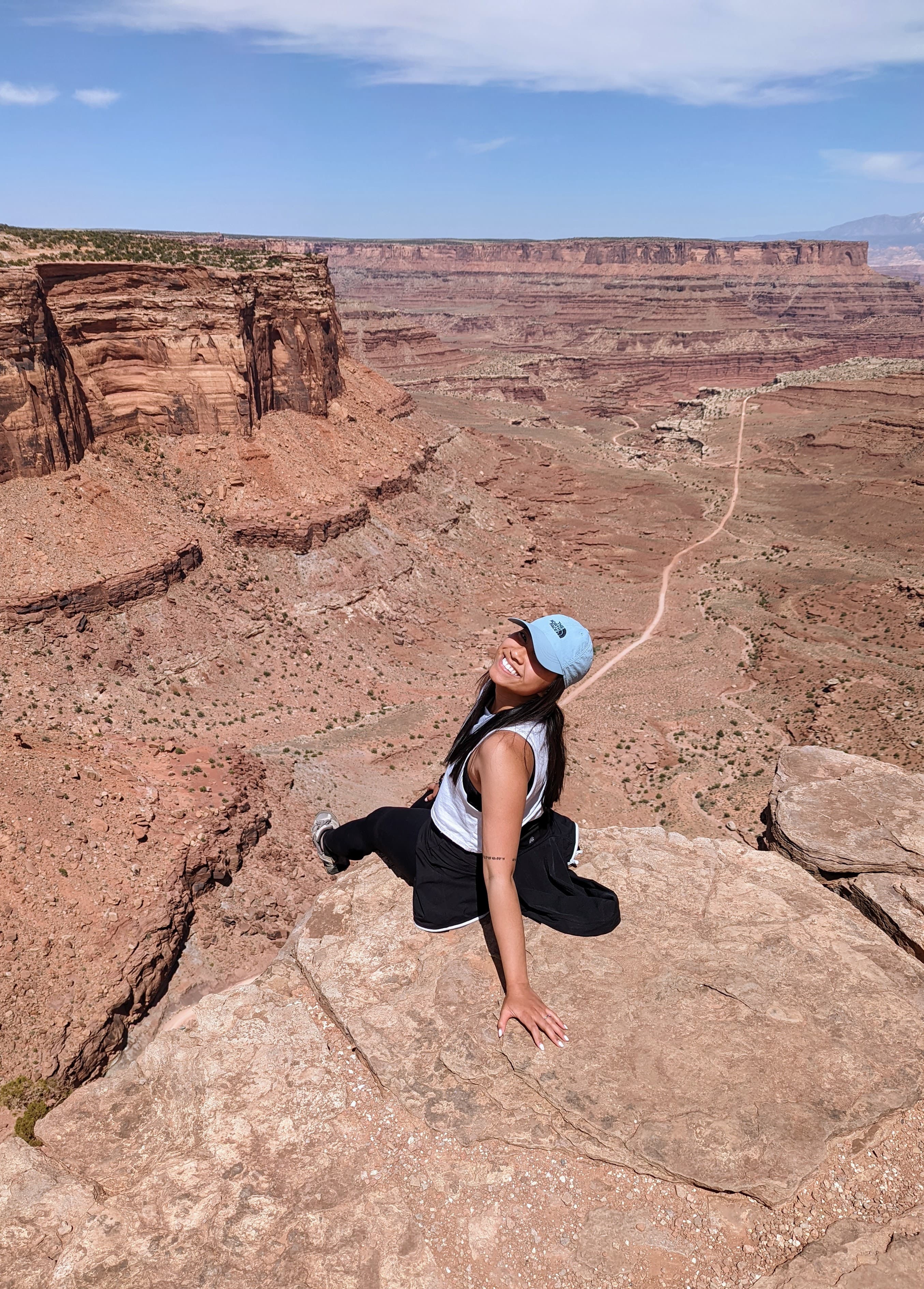 Woman laughing joyfully on a red rock canyon ledge in Utah with warm natural light